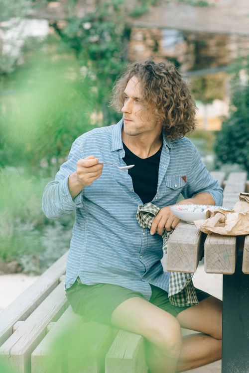 Free Man eating at a picnic table outdoors, wearing casual attire, during the day. Stock Photo