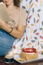 Person in White Polo Shirt and Blue Denim Jeans Sitting on White and Red Floral Textile