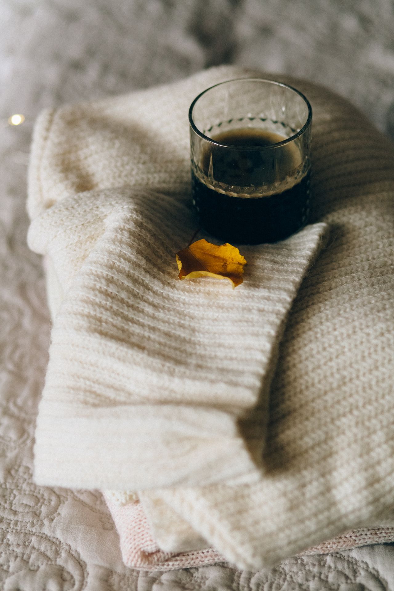 Folded cream knit blanket with a cup of coffee on top