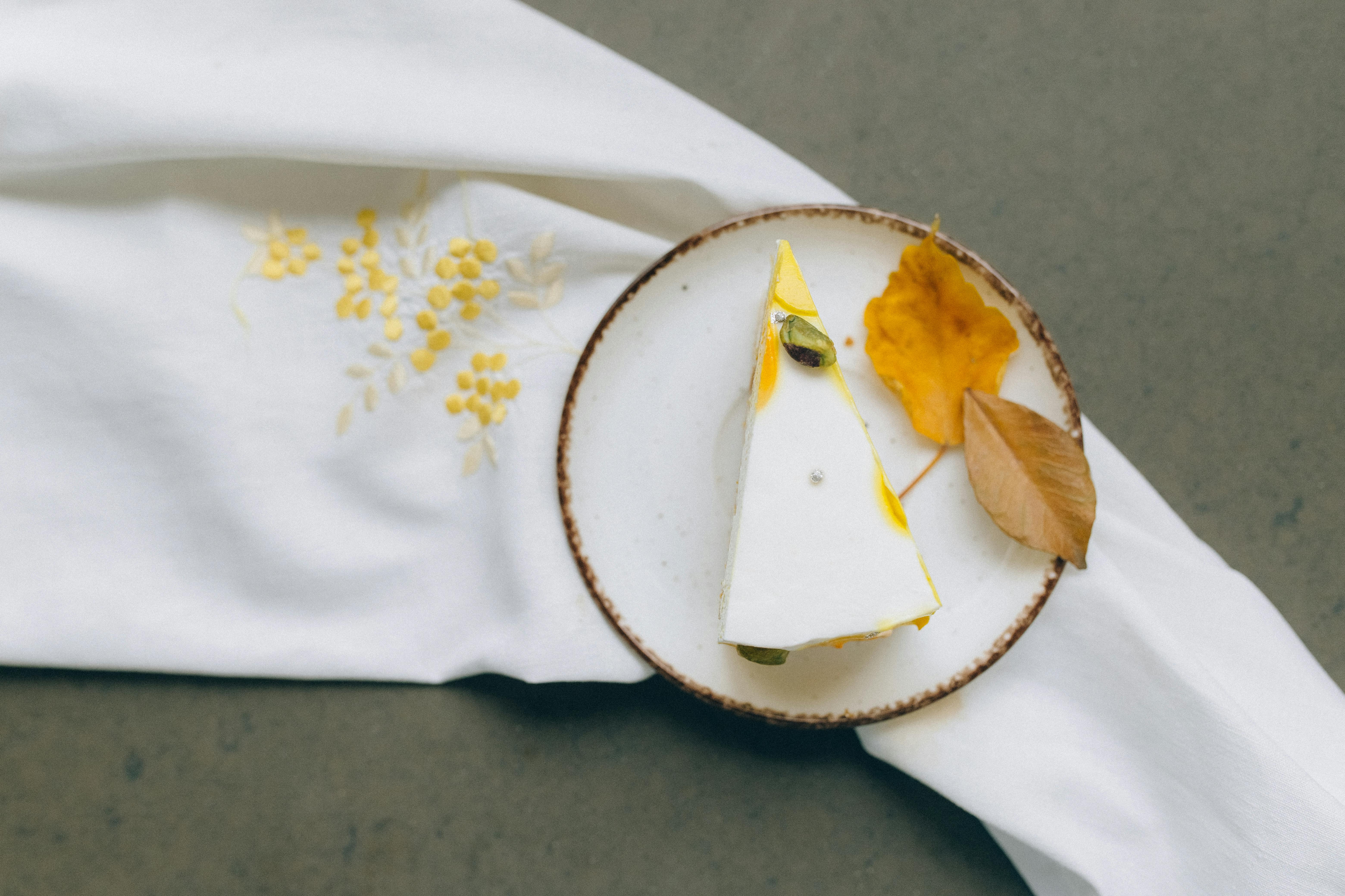 Elegant slice of cake on a plate with autumn leaves and fabric, perfect for fall-themed food photography.