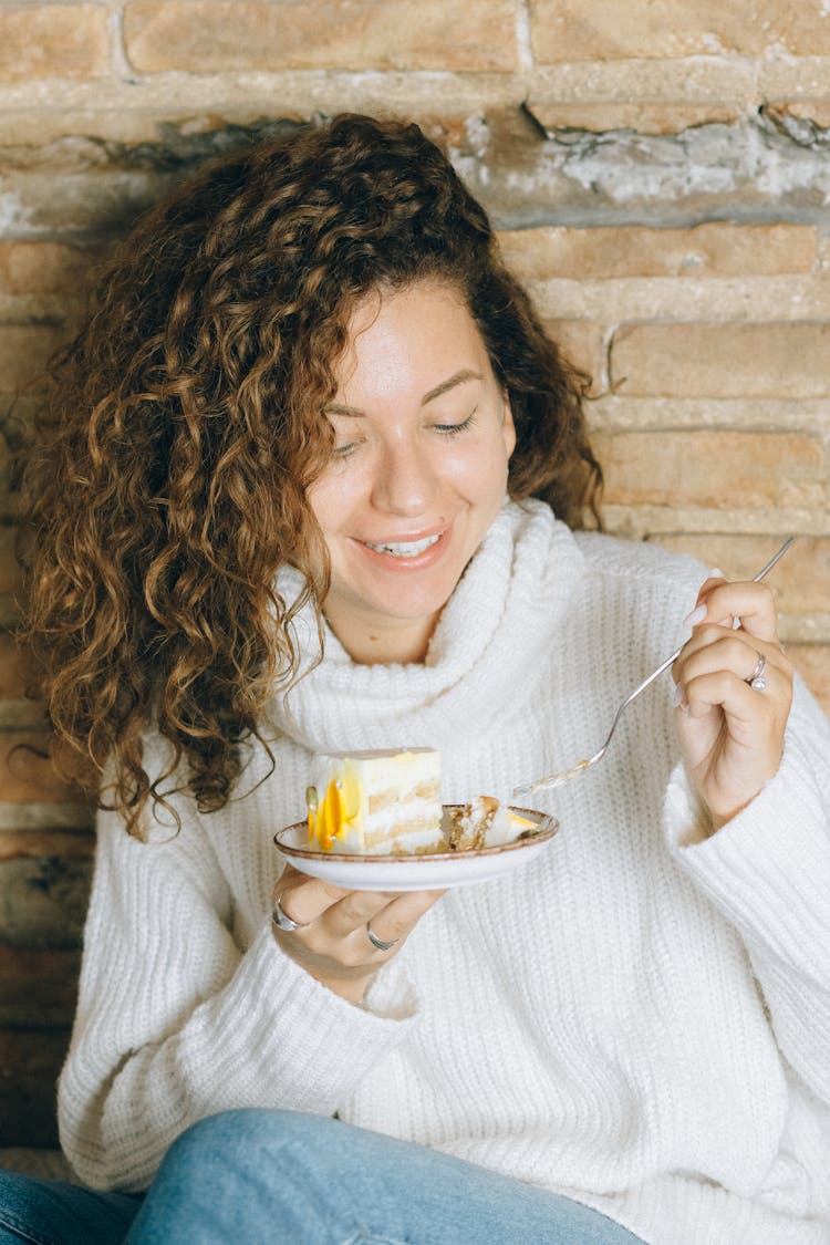 A Woman Eating A Slice Of Cake 