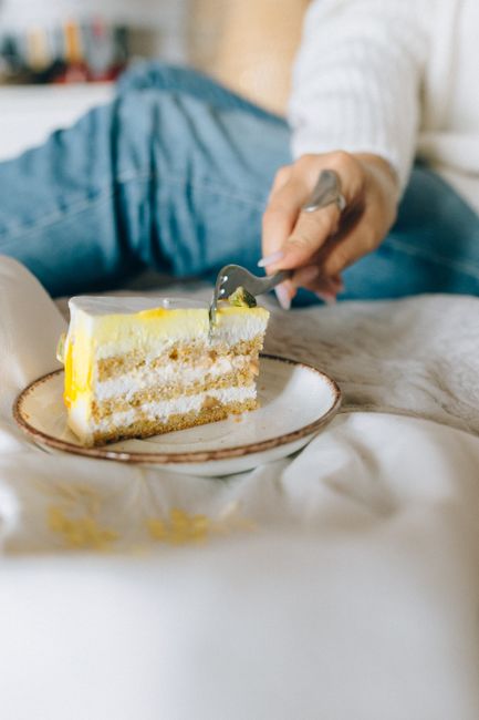 A delightful lemon cake slice on a plate with a person taking a bite, emphasizing indulgence and taste.