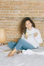 Woman in White Sweater and Blue Denim Jeans Sitting on Brown Wooden Table