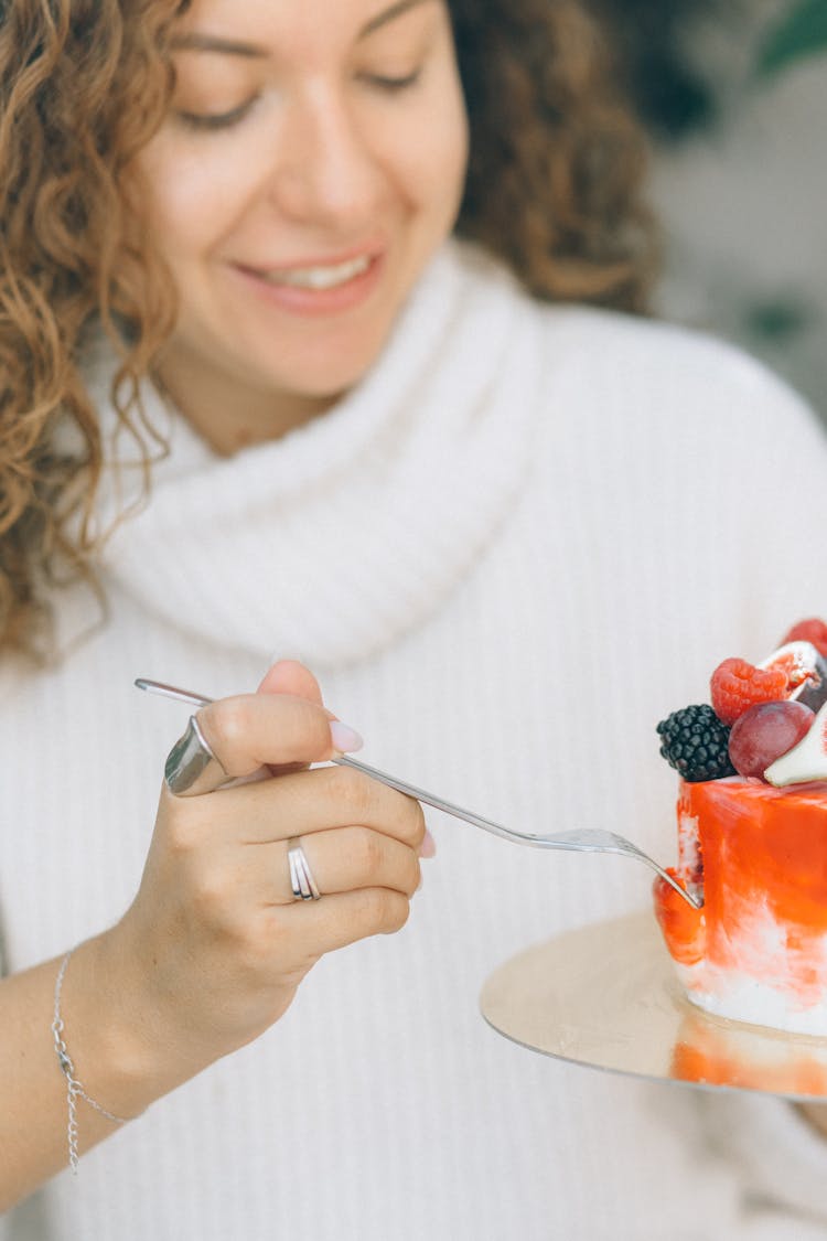 Woman Eating A Cake With Fruits Topping