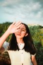 一个十几岁的女孩站在户外，保护眼睛免受夏日阳光的照射，构成了一幅宁静而沉思的肖像