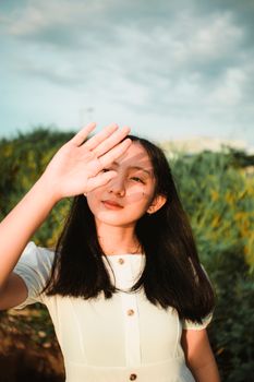 一个十几岁的女孩站在户外，保护眼睛免受夏日阳光的照射，构成了一幅宁静而沉思的肖像