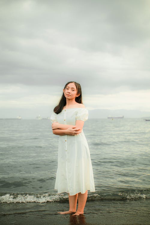 Young Woman in White Dress standing on Seashore 