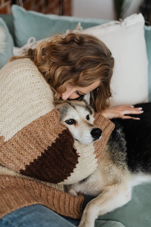Free Woman Hugging a Dog While Lying on a Sofa Stock Photo