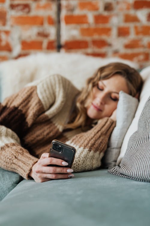 Relaxed Woman in knitted Sweater using a smartphone 