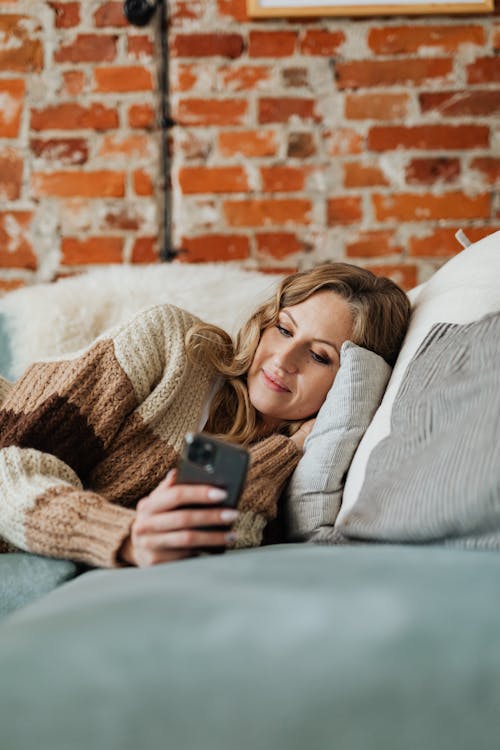 Relaxed Woman in knitted Sweater using a smartphone