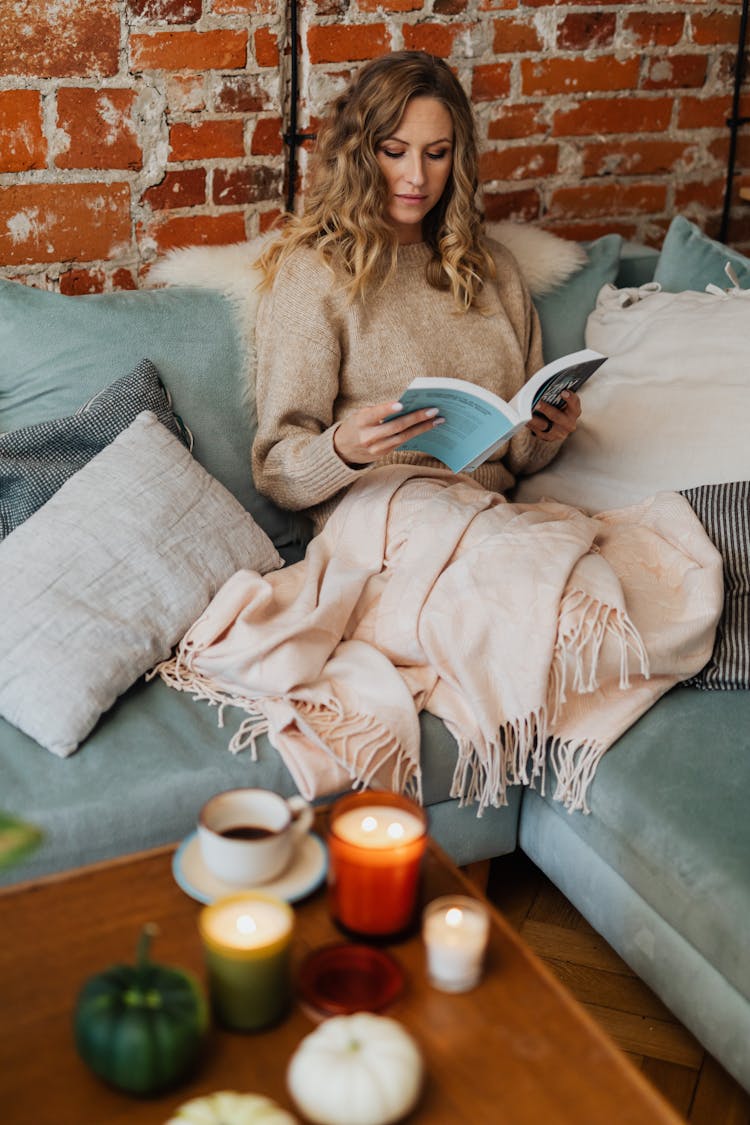 A Woman Reading A Book While Sitting On A Couch