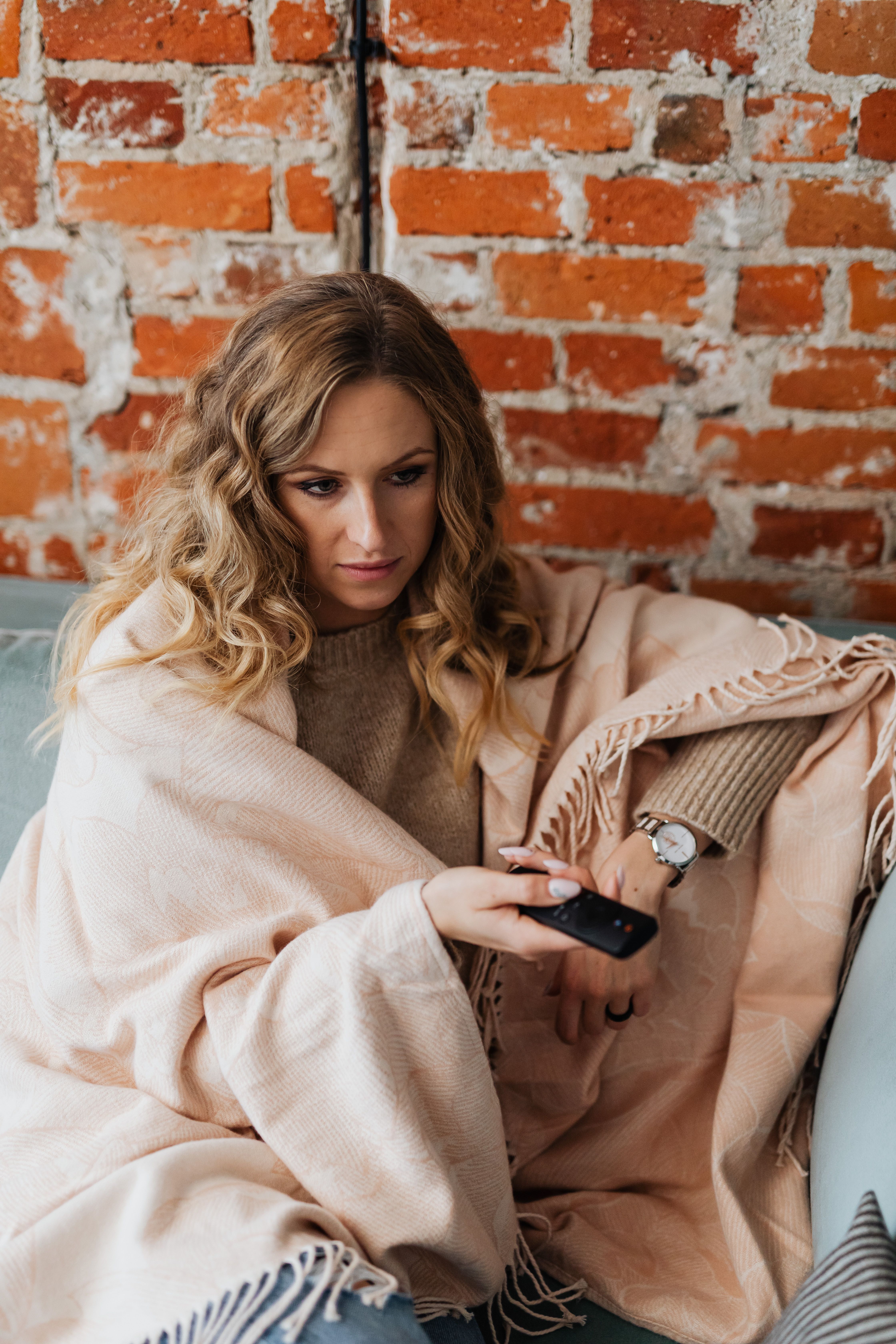 Woman in Beige Coat Leaning on Brown Brick Wall · Free Stock Photo