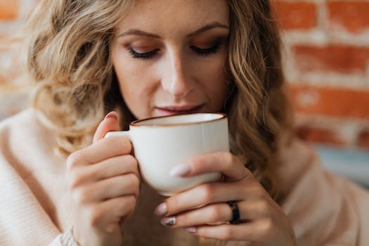 A close-up shot of a woman enjoying a warm cup of coffee indoors.