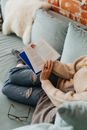 Person in Blue Denim Jeans Sitting on Gray Couch