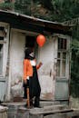 A Scary Man Holding a Red Balloon in Front of the Abandoned House
