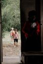 两个孩子小心翼翼地走近森林中一扇画着阴暗小丑的门