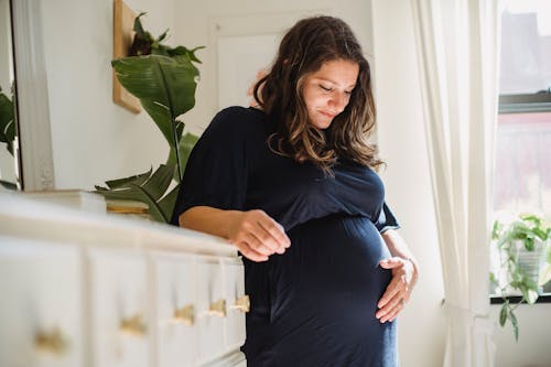 家の部屋でおなかを愛撫する妊婦の笑顔