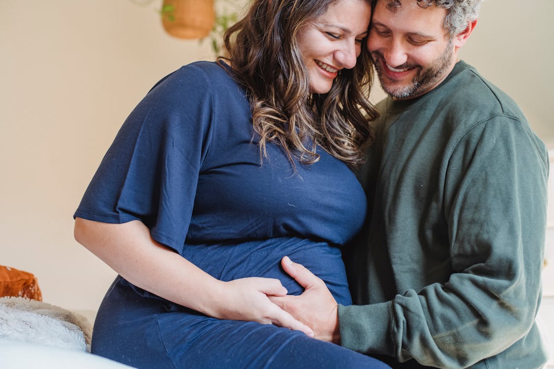 Happy pregnant couple caressing on bed