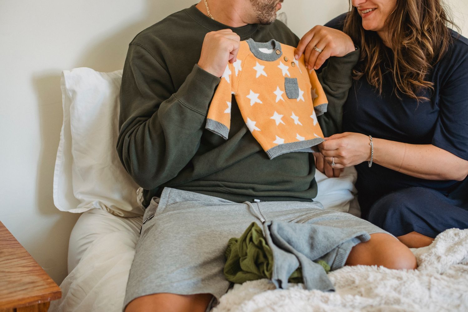 Couple préparant sereinement les premiers vêtements de son bébé avant la naissance