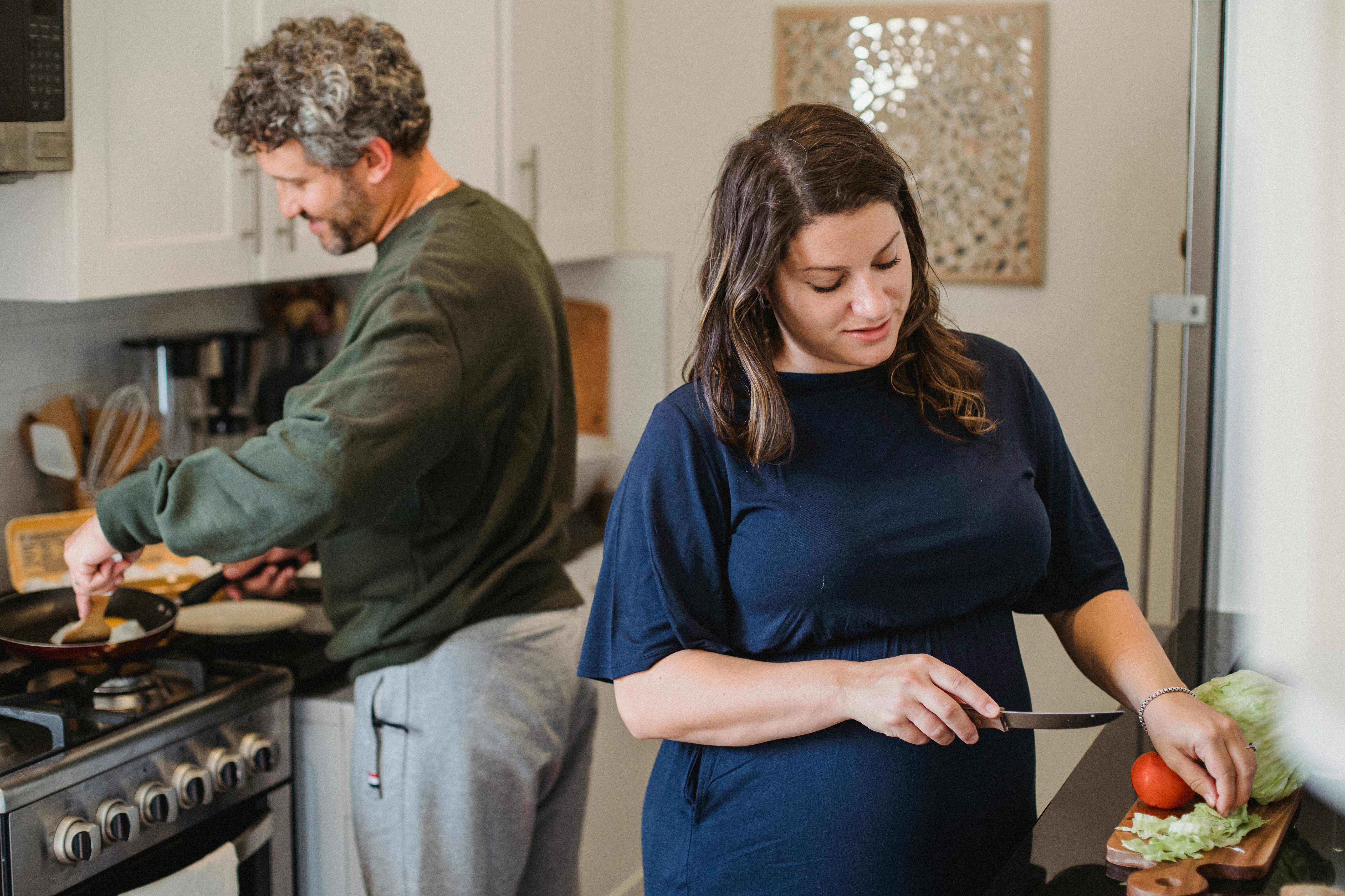 cheerful couple cooking dinner in kitchen