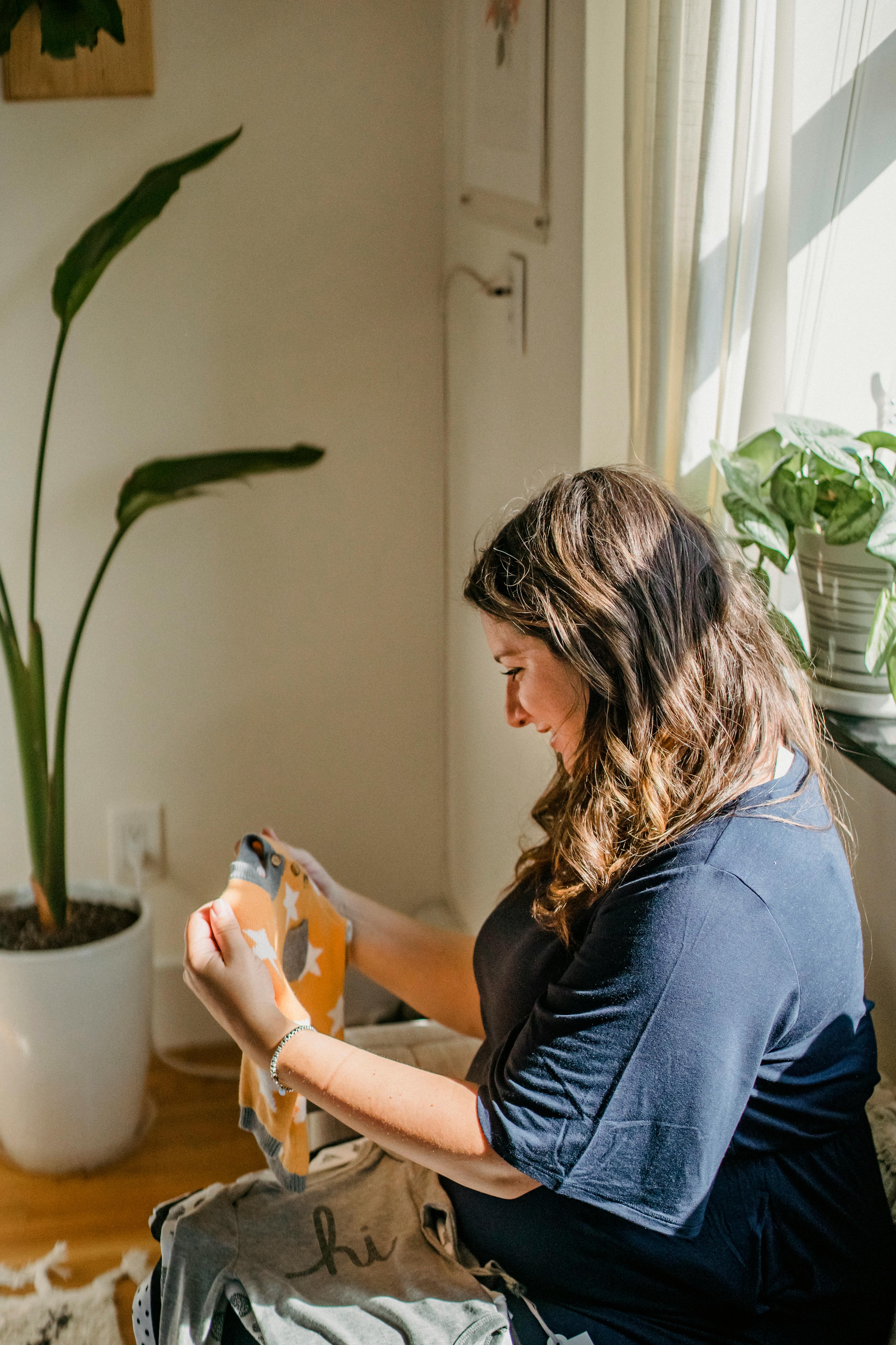 happy pregnant woman choosing clothes for baby