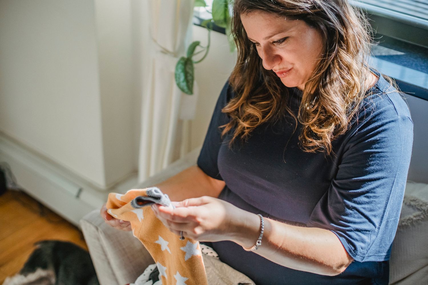 Femme enceinte souriante organisant les affaires de naissance dans un intérieur ensoleillé