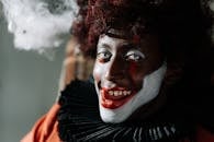 这幅黑暗而令人毛骨悚然的肖像中，小丑的创意妆容、非洲式发型和幽灵般的表情，完美契合了万圣节氛围