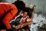 昏暗的房间里，成人不祥地俯身，而儿童在方格椅子上遇险