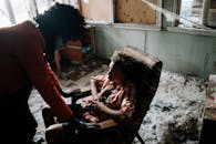 一个穿着成人服装、神情惊恐的孩子，隐约出现在昏暗的房间里