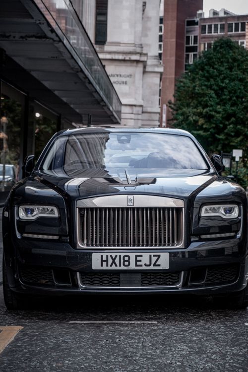 Free Front view of a luxury car parked on a city street, showcasing its elegant design. Stock Photo