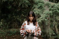 一个年轻女孩若有所思地站在宁静的森林里，四周环绕着郁郁葱葱的绿植