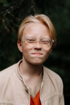 一个戴眼镜的十几岁男孩在户外眯着眼睛的特写肖像