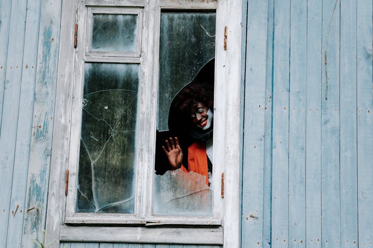 Sinister Clown Waving On A Shattered Window 