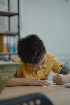 教室里，一个年轻的学生正专注地在桌子上写字