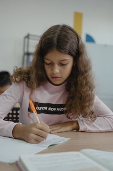 教室里，一个年轻女孩正专注地在笔记本上写着笔记