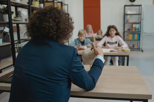 A teacher explains anatomy using a skull model in a classroom setting with students.