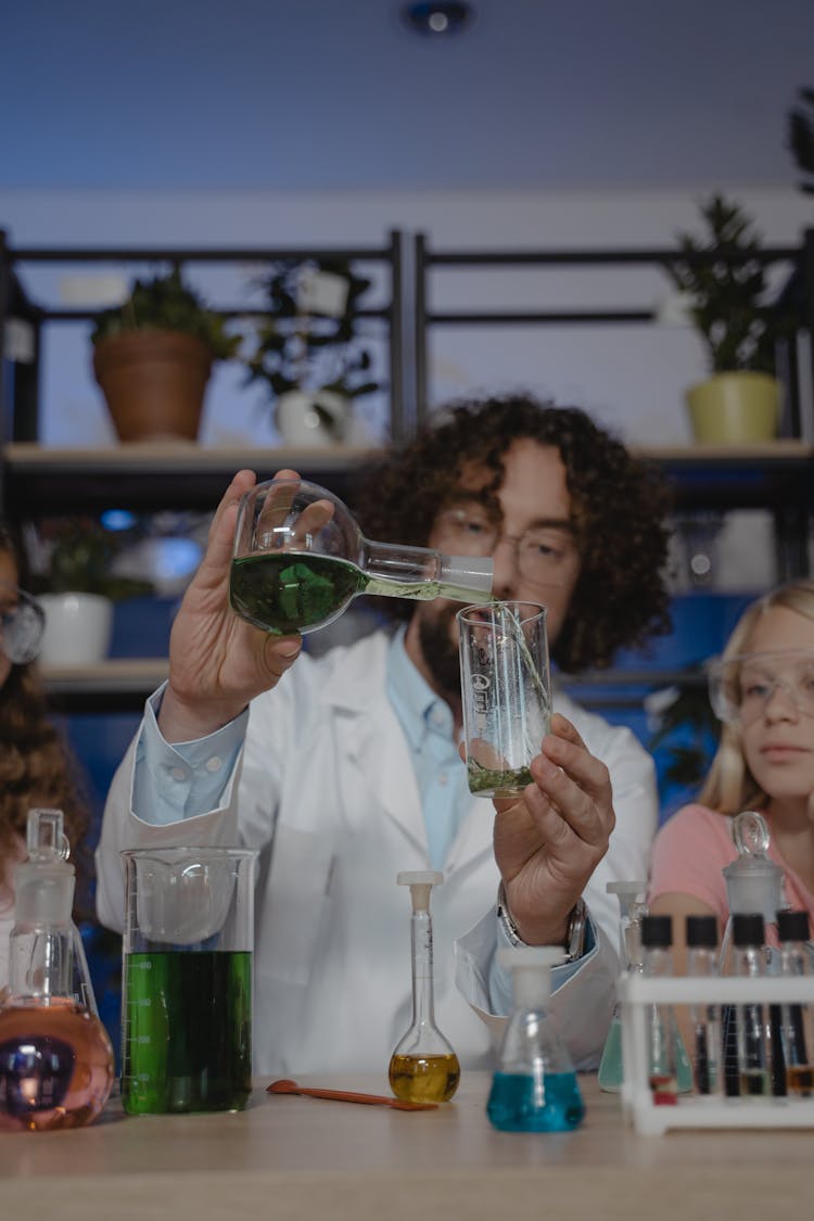 Teacher Pouring A Chemical To A Beaker