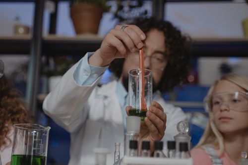 Free Engaging chemistry class with a teacher and students conducting a science experiment with beakers and test tubes. Stock Photo