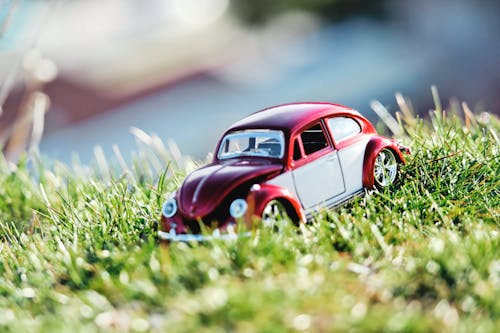 Red and White Beetle Car Toy on Grass Field in Bokeh Photography