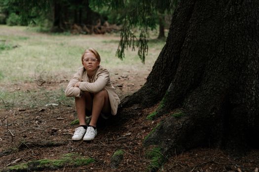 Girl in White Dress Sitting on Ground Beside Tree