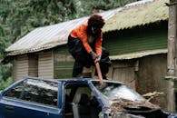 一名穿着戏服的小丑令人毛骨悚然，手持大锤在户外猛烈砸碎汽车挡风玻璃