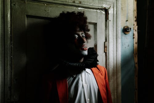 Scary Clown Smoking while Leaning on Wooden Door