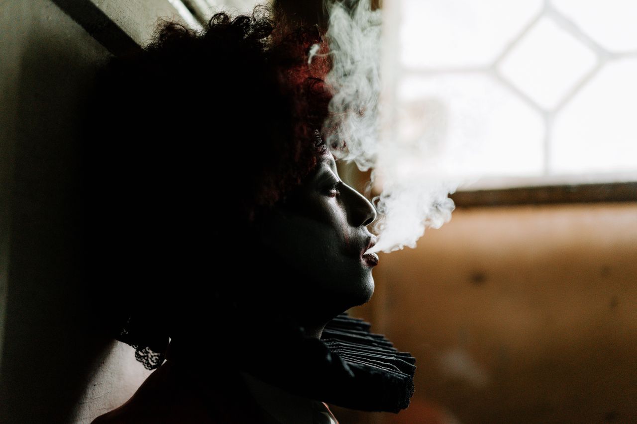 side profile of a clown smoking indoors creating a moody dramatic atmo