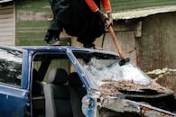 一名男子在户外用大锤猛烈砸碎汽车挡风玻璃