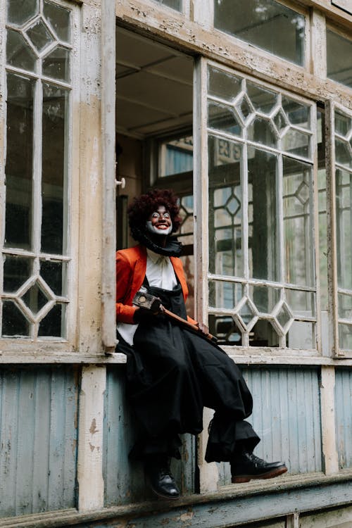 Evil Clown Holding a Sledge Hammer Sitting on Window