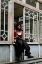 一个穿着戏服的幽灵小丑坐在一栋废弃的建筑里，手里拿着一把大锤