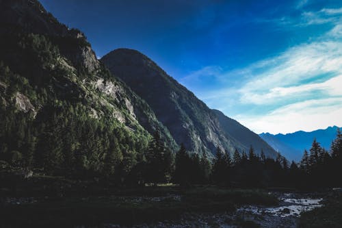 Spectacular scenery of wooded mountains and valley with coniferous trees against blue cloudy sky