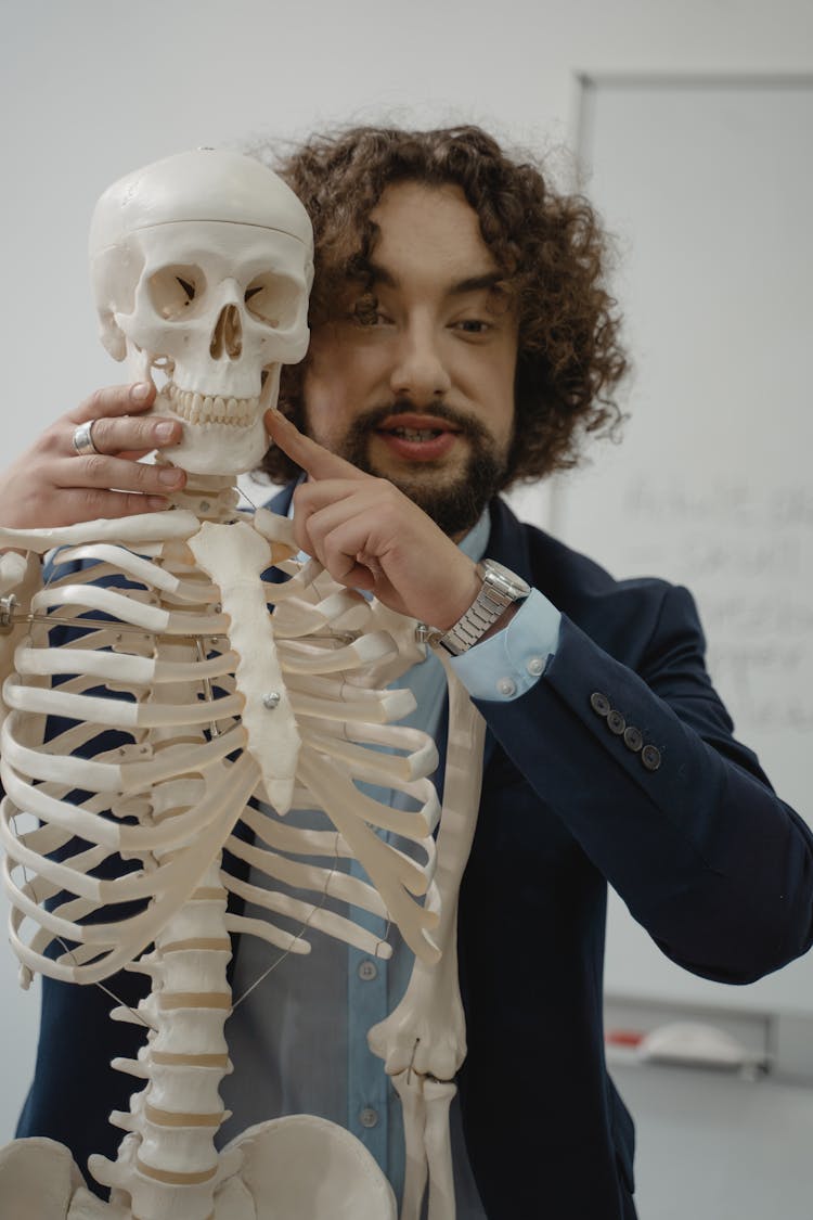 Teacher Pointing At A Human Skeleton