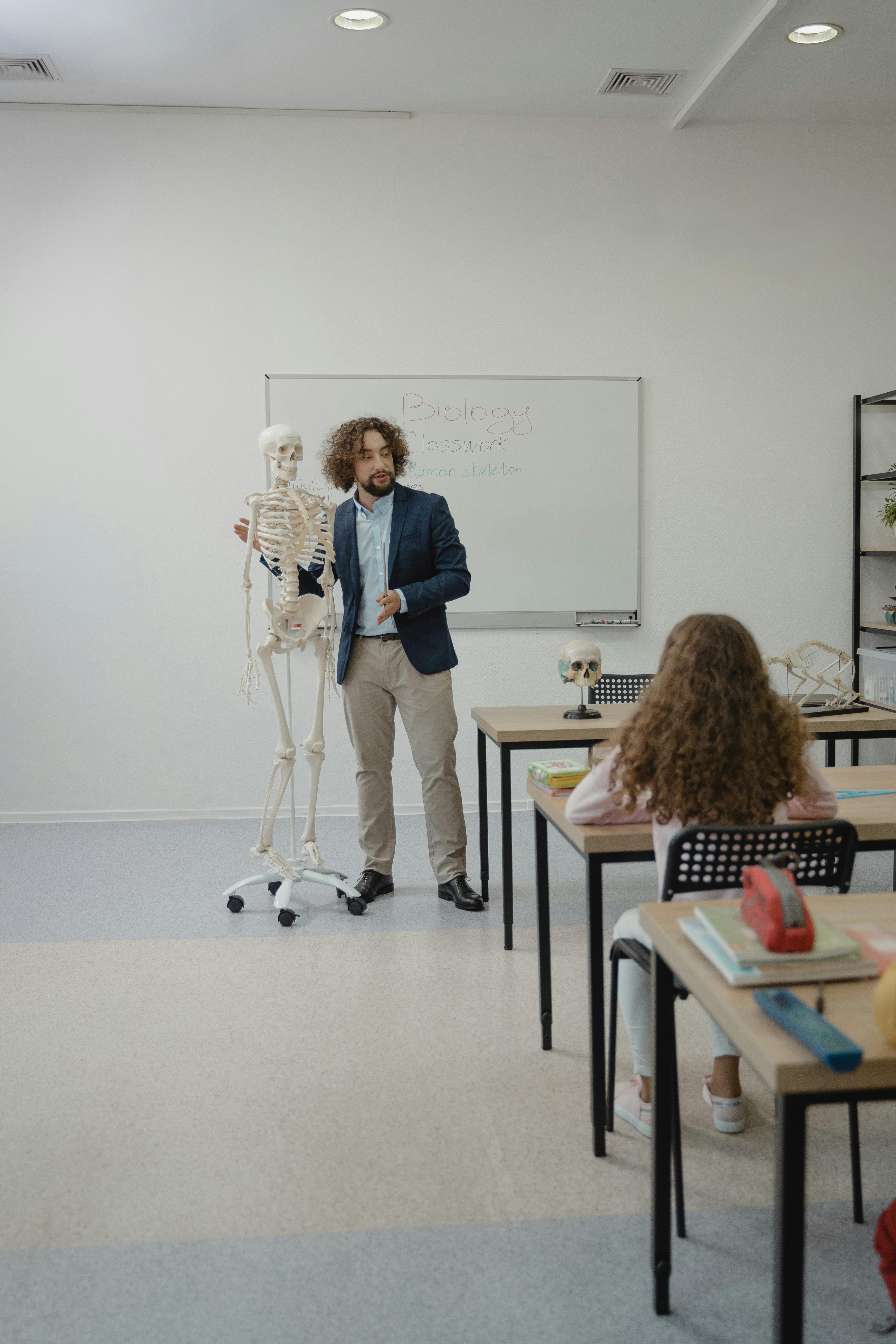 a man standing beside a skeleton teaching in a class