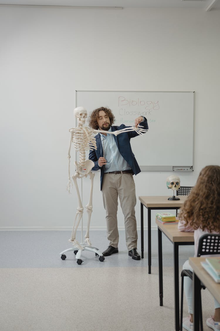 A Man Standing Beside A Skeleton While Teaching In A Class